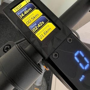 Op de afbeelding: Close-up van het display van een elektrische scooter met ritgegevens. Het scherm toont de gemiddelde snelheid, de afgelegde afstand, de verstreken tijd en de resterende actieradius. Het display is zwart met gele en blauwe tekst. Het stuur van de scooter is ook zichtbaar.