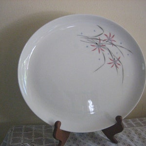May include: White oval serving platter with a floral design in shades of pink and gray. The design features stylized flowers and leaves.