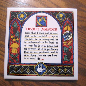 May include: Square ceramic tile with a stained-glass design. The tile features a central text in red, with a border of colorful illustrations including stars, grapes, and a dove. The text reads "DIVINE MASTER".