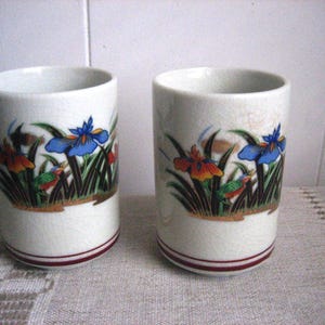 May include: A handmade wooden sign with the text "Welcome" in a playful font. The sign is painted white with a distressed finish, and features a decorative floral design in shades of pink and green. It measures approximately 12 inches wide and 6 inches tall.