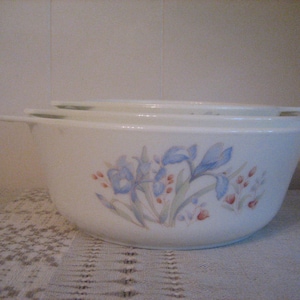 May include: Three white ceramic bowls with a floral design featuring blue and pink flowers. The bowls are stacked on top of each other.