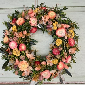 Flowery door wreath made of dried flowers in fiery colors