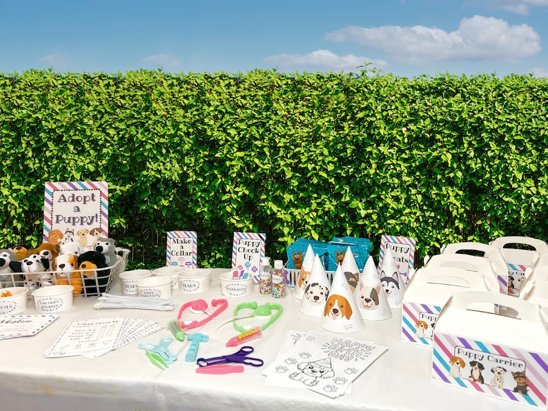 May include: A party table set up for a puppy-themed party. There are several activities for kids, including making a collar, a puppy check-up, and coloring a puppy. There are also several puppy-themed party favors in boxes.