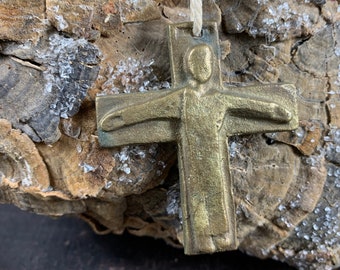 May include: A bronze cross pendant with a figure of Jesus Christ. The cross is attached to a string.