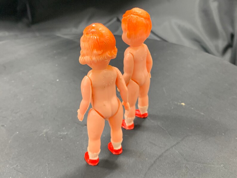 Pode incluir: Duas bonecas de pl&aacute;stico com sapatos vermelhos e cabelo laranja. As bonecas est&atilde;o de costas uma para a outra.