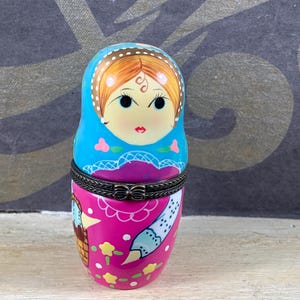 Peut inclure: Une poupée russe en porcelaine rose et bleue avec un visage peint et des détails floraux. La poupée est un souvenir russe traditionnel.