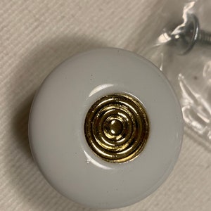 May include: White ceramic cabinet knob with a gold concentric circle design.
