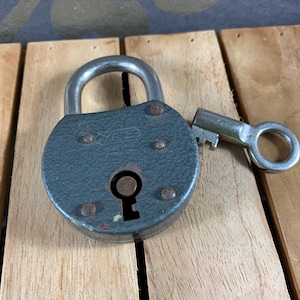 May include: A vintage padlock with a green metal body and a silver key. The padlock has a keyhole and several small rivets. The key is silver and has a round handle.