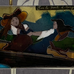 Op de afbeelding: Rechthoekig kunstwerk met figuren op een boot, met de tekst "Sur le Pont d'Avignon". Het kunstwerk toont een vrouw met een hoed en een andere figuur, met een donkerblauw, groen en goud kleurenschema.