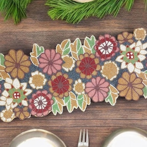 Puede incluir: Un camino de mesa de cuentas con un diseño floral en tonos de rosa, rojo, dorado y blanco. El camino de mesa está hecho de cuentas pequeñas y tiene un fondo azul oscuro.