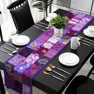May include: Purple and white patchwork table runner with a floral design. The runner is on a black table with two place settings.