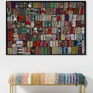 May include: A colourful patchwork wall tapestry with a black background and a variety of geometric and floral patterns. The tapestry is framed in black and hangs above a multi-coloured striped bench with a gold metal frame.