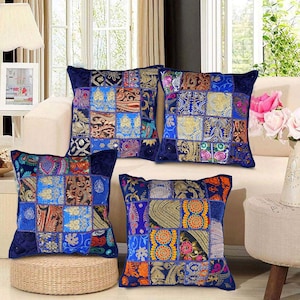 Könnte beinhalten: Vier blaue quadratische Kissen mit Patchwork-Muster in verschiedenen Farben und Mustern. Die Kissen sind aus Stoff und haben eine samtige Textur.