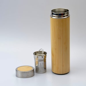 Op de afbeelding: Een reistheebeker van bamboe en roestvrij staal met een ingebouwde thee-infuser. De beker heeft een bamboe buitenkant en een roestvrijstalen deksel en infuser.