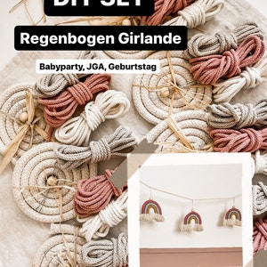 Könnte beinhalten: DIY-Set zum Basteln einer Regenbogen-Girlande. Das Set enthält mehrere Spulen mit Seil in beige und rosa. Das Bild zeigt auch eine fertige Regenbogen-Girlande mit drei Regenbogen-Dekorationen, die an einer Schnur hängen.