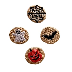 Peut inclure: Quatre écussons circulaires sur le thème d'Halloween. Ils présentent une toile d'araignée noire, un fantôme blanc, une chauve-souris noire et une citrouille rouge. Les écussons ont un fond beige.