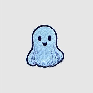 Op de afbeelding: Een blauwe en zwarte geborduurde geest met een glimlachend gezicht. De geest is een schattig en fantasierijk ontwerp, perfect om een ​​beetje Halloween-plezier aan elk project toe te voegen.