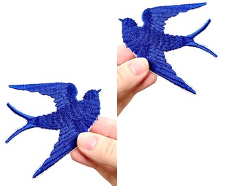 May include: Two blue embroidered swallow bird patches. The patches are shown in the hands of two different people.