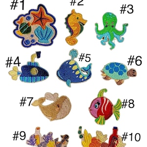 Könnte beinhalten: Zehn bunte, gestickte Bügelbilder mit verschiedenen Meeresbewohnern, darunter ein Seestern, ein Seepferdchen, ein Oktopus, ein U-Boot, ein Wal, eine Schildkröte, ein Fisch und eine Flasche mit einem Seestern und Muscheln.