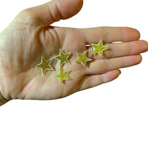 May include: Six gold star-shaped iron-on patches with white outlines.