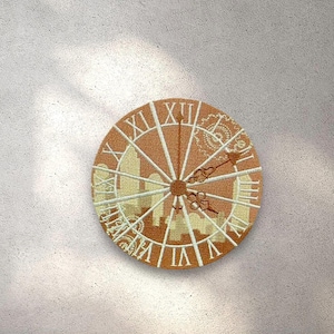 May include: A round, brown clock face with white Roman numerals and a cityscape design. The clock hands are pointing to the time of 12:00.