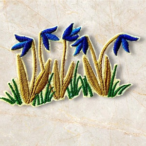 以下が含まれることがあります： 青い花が緑と金の茎と葉で集まっている刺繍パッチ。衣服、バッグ、その他のアクセサリーに自然のタッチを加えるのに最適です。