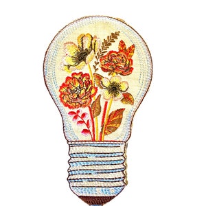 Op de afbeelding: Een geborduurde patch in de vorm van een gloeilamp met een bloemenmotief. De lamp is wit met een blauwe voet en de bloemen zijn rood, oranje en geel.