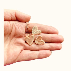 Op de afbeelding: Drie gouden, geborduurde hartvormige patches.