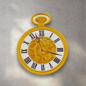K&ouml;nnte beinhalten: Eine goldfarbene Taschenuhr mit r&ouml;mischen Ziffern auf einem wei&szlig;en Zifferblatt. Das Zifferblatt der Uhr hat ein detailliertes, kompliziertes Design aus Zahnr&auml;dern und Uhrwerk.