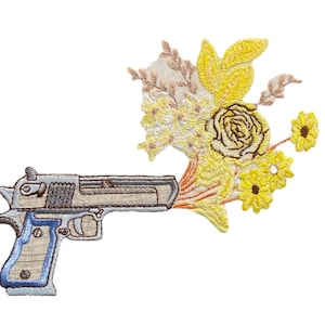 May include: An embroidered patch depicting a gun with a bouquet of yellow flowers coming out of the barrel.