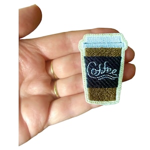 Könnte beinhalten: Ein gestickter Aufnäher mit einem Kaffebecher und dem Wort "Coffee" darauf, in Braun und Weiß.