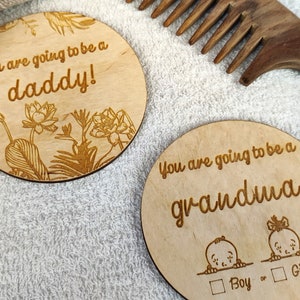 May include: Two wooden plaques with engraved messages. The first plaque has a floral design and says "You are going to be a daddy!" The second plaque has a boy and girl illustration and says "You are going to be a grandma!" with a checkbox for "Boy" or "Girl".