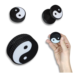 May include: Black and white yin yang symbol grinder with a textured outer ring. The grinder is made of two pieces that fit together.