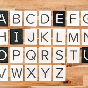 Uppercase letters are a great educational tools. Montessori sandpaper letters are lined up on a wooden table.