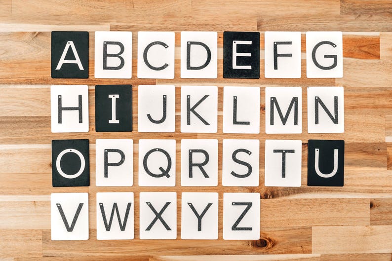 Uppercase letters are a great educational tools. Montessori sandpaper letters are lined up on a wooden table.