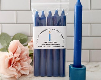 May include: A pack of six dark blue unscented spell candles, 5 inches tall, with a label that reads "The Stone Sanctuary Shop Established 2021 Unscented 5' Tall Dark Blue Spell Candles www.thestonesanctuary.com".