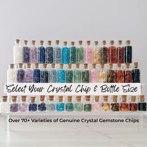 May include: A display of small glass bottles filled with various colored crystal chips. The bottles are arranged on tiered shelves, with cork stoppers. Text on the display reads "Select Your Crystal Chip & Bottle Size" and "Over 70+ Varieties of Genuine Crystal Gemstone Chips."