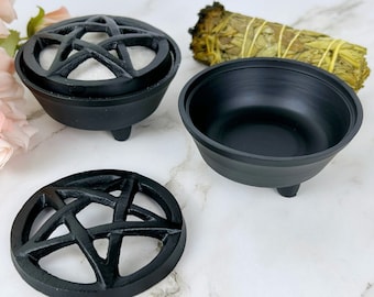 May include: Black metal incense burner with a pentagram design. The burner has three legs and a removable lid. The lid has a pentagram design and a small hole in the center.