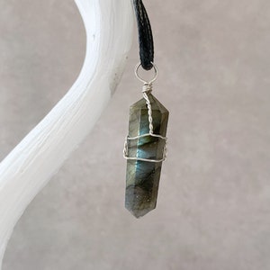 May include: A silver wire wrapped labradorite crystal pendant on a black cord.