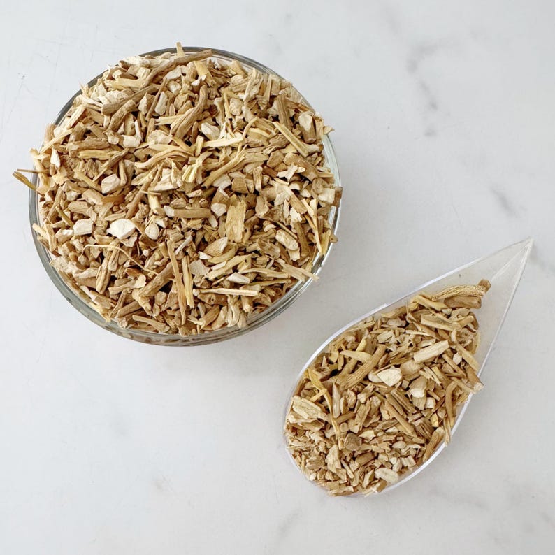 May include: A clear glass bowl and a teardrop-shaped dish filled with chopped, dried, tan-colored roots. The roots have a variety of shapes and sizes, with some pieces appearing lighter in color. The items are arranged on a white marble surface.
