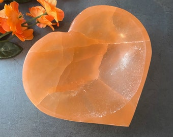 May include: A heart-shaped orange calcite dish. The dish is made of natural stone and has a smooth, polished surface.