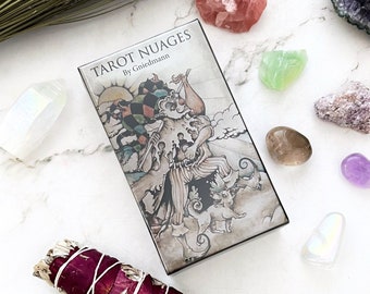 May include: Tarot Nuages deck box with a colorful illustration of a jester-like figure with a dog on a cloud background. The box is silver with a black border and the text "Tarot Nuages by Griedmann" is printed on the front.