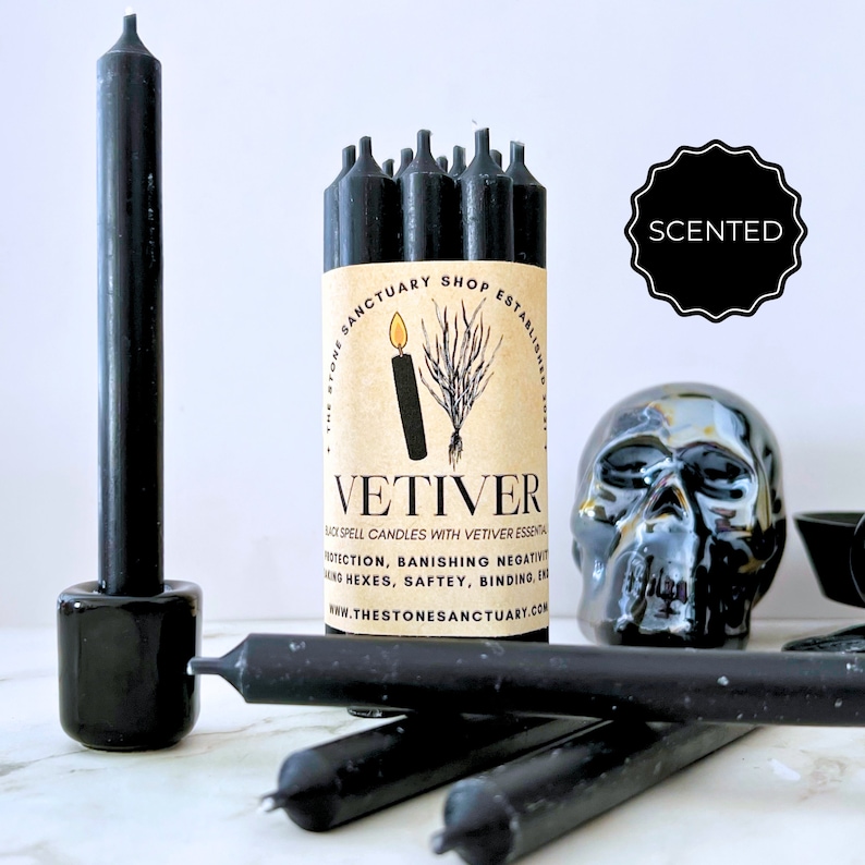 May include: Black Vetiver scented spell candles with a skull and candle holder. The candles are packaged with a label that reads "VETIVER" and "THE STONE SANCTUARY SHOP ESTABLISHED". The image also includes the word "SCENTED".