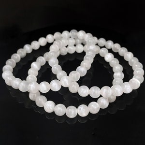 Peut inclure: Trois bracelets en pierres pr&eacute;cieuses blanches avec des perles rondes. Les bracelets sont empil&eacute;s les uns sur les autres.