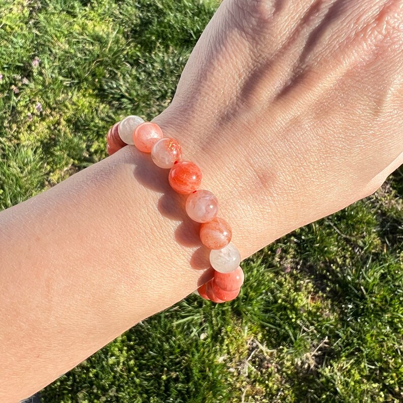 May include: A bracelet made of orange and white gemstone beads. The beads are round and have a smooth, polished finish.