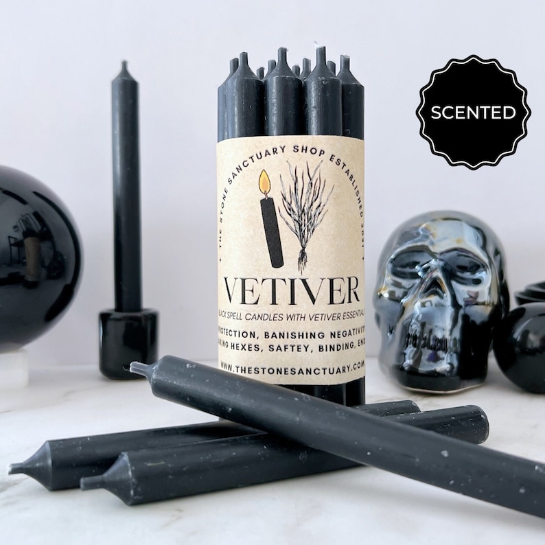 May include: Black Vetiver spell candles with a scented label. The candles are displayed with a black skull, a black sphere, and a black candle holder. The label reads "VETIVER" and "BLACK SPELL CANDLES WITH VETIVER ESSENTIAL OILS".