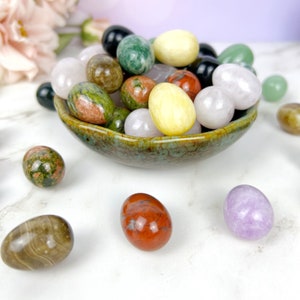 Puede incluir: Un cuenco lleno de piedras pulidas de varios colores, incluyendo piedras verdes, rojas, marrones, blancas y amarillas. El cuenco est&aacute; hecho de cer&aacute;mica y tiene un esmalte verde. Las piedras est&aacute;n dispuestas en un patr&oacute;n aleatorio.