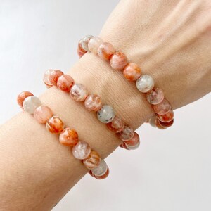 May include: Three layered bracelets made of orange and white sunstone beads.
