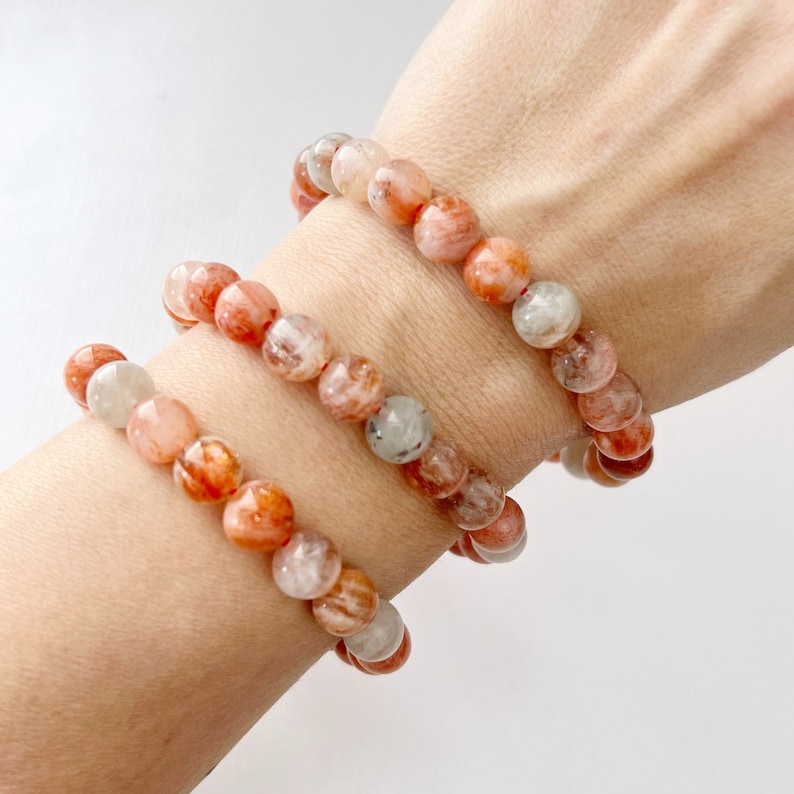May include: Three layered bracelets made of orange and white sunstone beads.