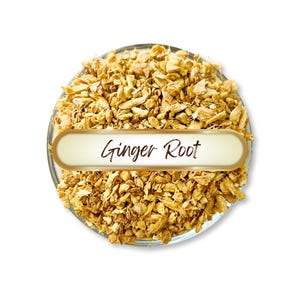 May include: A clear glass bowl filled with dried, chopped ginger root. A white and gold label across the bowl reads "Ginger Root" in a cursive font. The ginger is a light brown color.